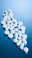 White pharmaceutical pills and tablets scattered on blue gradient background for medical healthcare and medicine concepts.