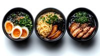 Asian noodle bowls with ramen, soft boiled eggs, teriyaki chicken, fresh herbs and sesame seeds served in black ceramic bowls on dark background.
