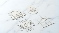 Elegant minimalist logo designs cut from white paper on marble surface showcasing modern branding concepts for corporate identity and business applications.