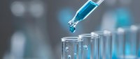 Laboratory pipette dropping blue liquid into test tube for scientific research and chemical analysis in modern lab setting.