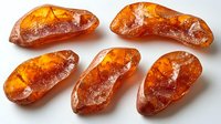 Raw amber stones with natural inclusions and translucent orange glow on white background, mineral specimens showing organic fossilized tree resin texture.