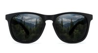 Black sunglasses with mountain forest landscape reflection in lenses showing pine trees and scenic valley view for outdoor adventure concepts.