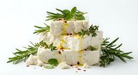 Fresh white cheese cubes with aromatic herbs rosemary thyme basil on white background. Gourmet dairy product for culinary cooking Mediterranean cuisine recipes.