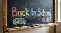 Back to school colorful chalk text on blackboard with school bus drawing, apple and books. Educational classroom concept for students and teachers.