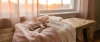 Vintage brass keys with a welcome tag resting on soft linen fabric near a sunlit window, evoking warmth and new beginnings.