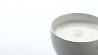 Fresh milk in white ceramic cup with foam on clean white background for dairy product advertising and healthy breakfast concepts.
