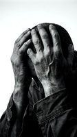 Stressed middle-aged man covering face with hands showing despair and mental health struggles in dramatic black and white portrait.