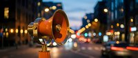 Orange vintage megaphone on city street at dusk with blurred traffic lights and urban bokeh background for communication and announcement concepts.