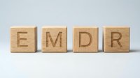 Wooden blocks spelling EMDR representing eye movement desensitization and reprocessing therapy concept for mental health treatment and trauma recovery.