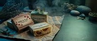 Artisanal soap bars with eucalyptus and natural ingredients displayed on kraft paper with dried botanicals and stones on teal surface for wellness and spa product marketing.