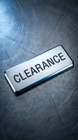 Shiny metallic clearance badge on brushed steel surface, conveying retail sale, discount, and promotional concepts for business use.