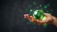 Hand holding glowing green earth globe with bokeh lights on dark background representing environmental protection and sustainability concepts.