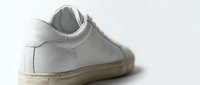 White leather sneaker closeup on light background, showcasing minimalist casual footwear design with clean lines and subtle texture details.