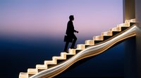 Silhouetted male professional climbing illuminated staircase against twilight sky, representing career advancement, ambition, and business success for corporate and motivational content.