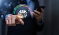 Businessman touching digital risk management gauge interface with colorful meter display showing assessment levels for corporate security analysis.