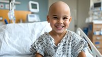 Young patient with bright smile wearing hospital gown sits upright in medical bed, displaying resilience and optimism during treatment in modern healthcare facility.