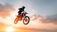 Motocross rider performing aerial stunt jump against dramatic sunset sky. Extreme sports action shot with silhouetted biker on dirt bike mid-flight during golden hour.