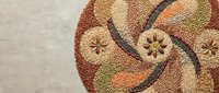 Traditional handwoven textile with intricate floral embroidery in warm earth tones featuring decorative stitching and ornamental patterns on natural fabric.