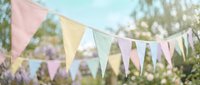 Colorful pastel bunting flags hanging outdoors in soft natural light creating festive party decoration atmosphere for celebrations and events.