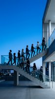 Business professionals climbing modern office staircase in corporate building during evening hours with city skyline view for teamwork concepts.