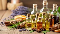 Natural essential oils in glass bottles with lavender, herbs and spices on wooden background for aromatherapy, wellness and spa treatments.