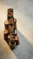Wooden letterpress blocks spelling SAVE stacked on coin piles representing financial savings and money management concepts for budgeting and investment planning.