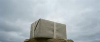 Burlap-wrapped parcel resting on a stone surface against a dramatic cloudy sky, evoking mystery, delivery, and rustic packaging concepts.