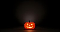 Glowing jack-o-lantern pumpkin with carved face and lit interior on dark background, isolated for Halloween designs, decorations, and seasonal marketing materials.