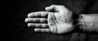 Male hand with open palm gesture against dark textured background, conveying offering, acceptance, or help concept for business and communication designs.