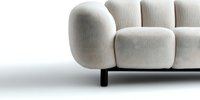 Modern minimalist cream sofa with rounded cushions and black metal legs on white background. Close-up view shows luxurious textured upholstery detail.