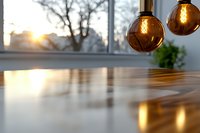 Modern pendant lights with amber glass globes hanging above wooden table surface, warm sunset glow through window creates cozy atmospheric lighting effect.