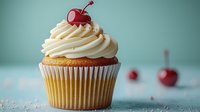 Vanilla cupcake with swirled buttercream frosting topped with maraschino cherry on turquoise background, selective focus creates dreamy dessert atmosphere.