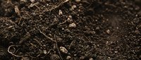 Rich dark fertile soil with organic matter and small stones creating natural earth texture for gardening and agriculture applications.