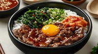 Korean bibimbap bowl with marinated beef, fresh spinach, kimchi, rice and raw egg yolk served in traditional stone bowl for authentic Asian dining experience.