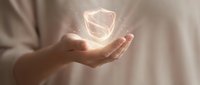 Hand holding glowing shield icon symbolizing data protection, cybersecurity, and digital safety for business and technology concepts.