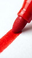 Red marker with cap creating vibrant stroke on white surface, suitable for art, design, education, and creative projects.