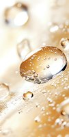 Macro photography of water drops on golden surface with bokeh effect, showing crystal clear liquid spheres with light reflections and delicate surface tension.