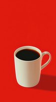 White ceramic mug filled with black coffee casting soft shadow on vibrant red background, minimalist composition for cafe menu or coffee advertising.
