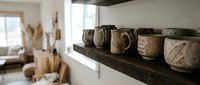 Rustic wooden shelf displaying potted plants with natural twine wrapping in bright, minimalist interior space for home decor and botanical styling.