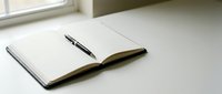 Open notebook with black pen on white desk near window for writing planning journaling office workspace productivity business education study notes.