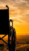 Silhouette of wheelchair against golden sunset sky with urban cityscape in distant background, symbolizing hope, accessibility, and independence for healthcare and disability awareness campaigns.