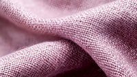 Soft pink linen fabric with natural texture and folds creates gentle waves and shadows, showing detailed weave pattern and fibers in macro photography.
