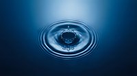 Water drop creating concentric ripples on deep blue surface, suitable for environmental, science, and wellness design projects.