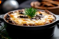 Golden baked casserole with melted cheese and fresh dill garnish in cast iron skillet. Comfort food ready to serve for family dinner or holiday meal.