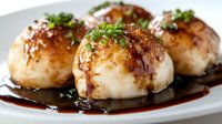 Pan-seared scallops with glossy brown sauce and fresh herbs on white plate. Gourmet seafood dish for restaurant menu or culinary presentation.