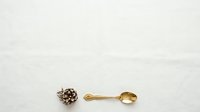 Vintage brass spoon and ornate metal decorative object arranged on neutral background for tableware, antique collecting, and home decor styling.