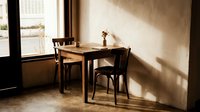 Cozy wooden dining table and chairs set in warm sunlit room with natural light streaming through window creating peaceful home interior atmosphere.