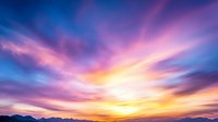 Dramatic sunset sky with vibrant purple and orange clouds streaking across horizon, silhouetted mountain range below creates peaceful nature landscape backdrop.