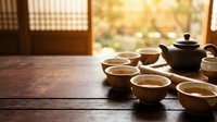 Traditional tea ceremony setup with ceramic teapot and cups on wooden table in warm sunlight streaming through window creating peaceful meditation atmosphere.