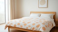Minimalist bedroom interior with wooden bed frame and polka dot duvet cover in peach and white. Natural light from window creates serene atmosphere.